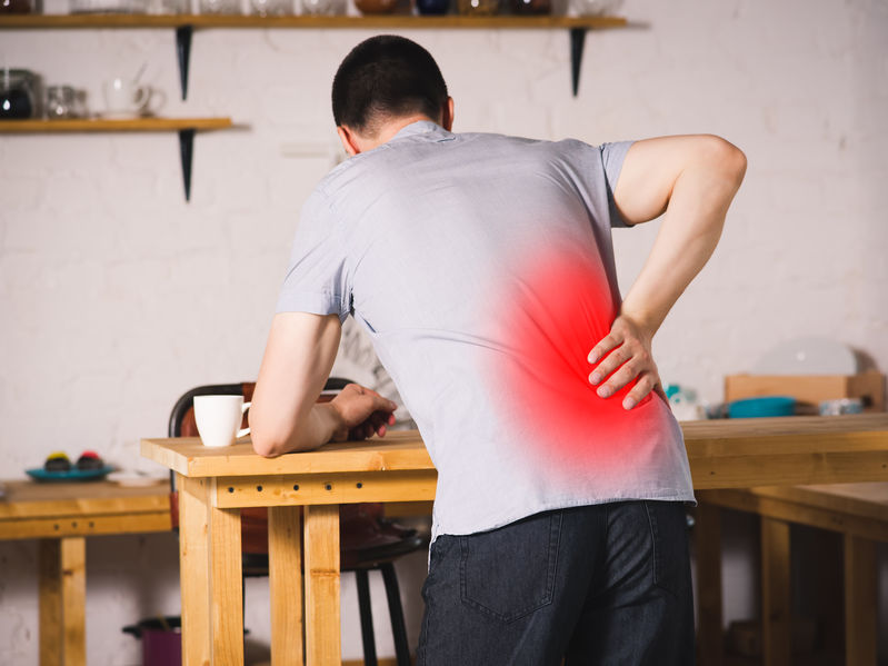 Man grabbing his aching lower back thanks to chronic inflammation