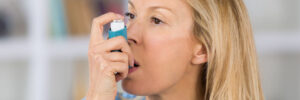 Closeup of a woman with asthma using her inhaler.