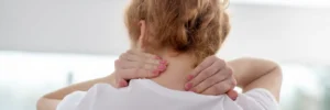 Red-haired female patient massaging her painful neck