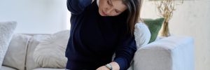 Woman massaging neck while sitting on couch